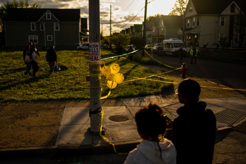 People attend a vigil across the street from Tops Friendly Markets.