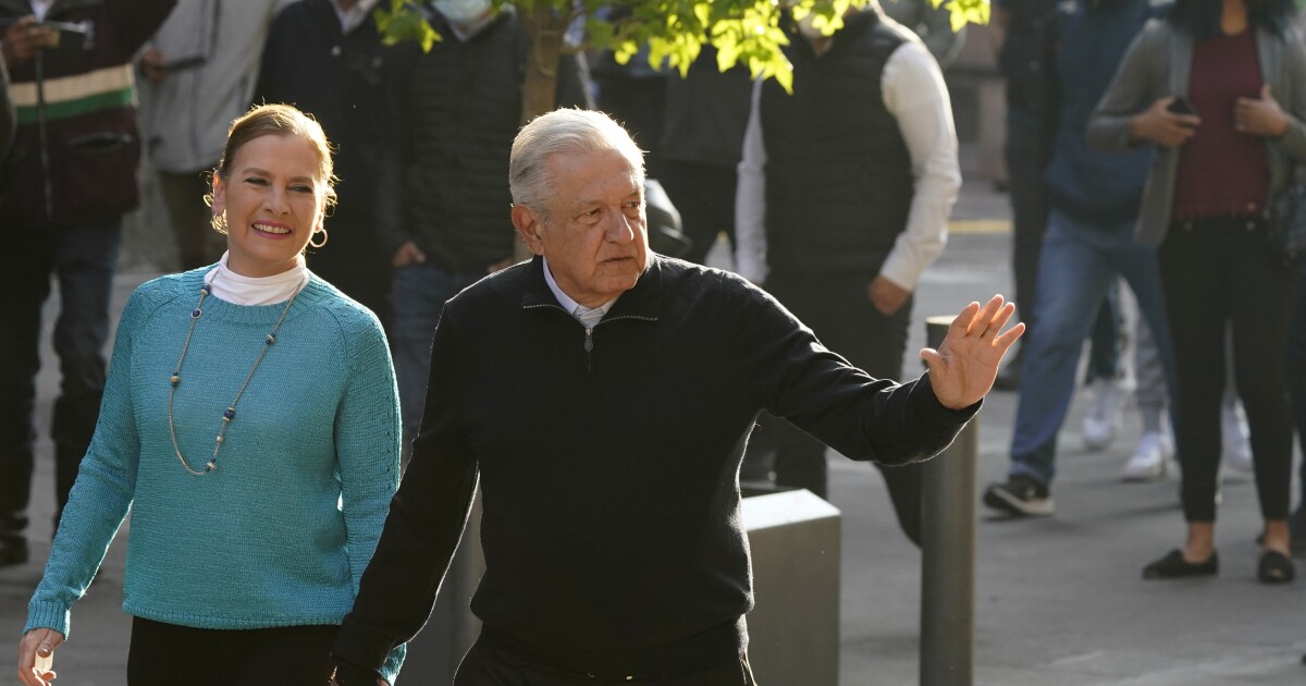 Mexico´s President Andres Manuel Lopez Obrador walks with his wife Beatriz Gutierrez Muller, before voting in a national referendum on whether he should end his six-year term barely midway through or continue to the end, outside their polling station in Mexico City, Sunday, April 10, 2022. (AP Photo/Eduardo Verdugo)