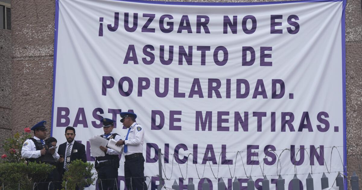 Security personnel stand at a federal court as unionized federal court workers gather outside to strike over reforms that would make all judges stand for election in Mexico City, Monday, Aug. 19, 2024. The sign reads in Spanish