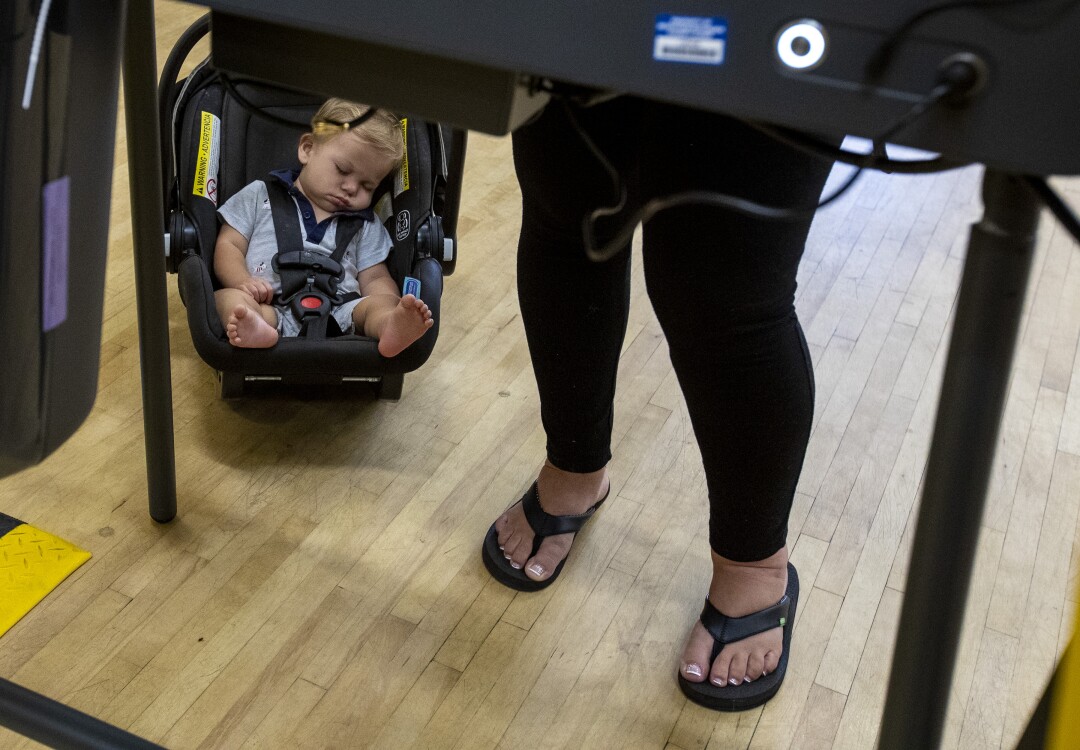 11-month-old Boden Heiderscheidt naps while his mom Jazmin Zamora casts a ballot