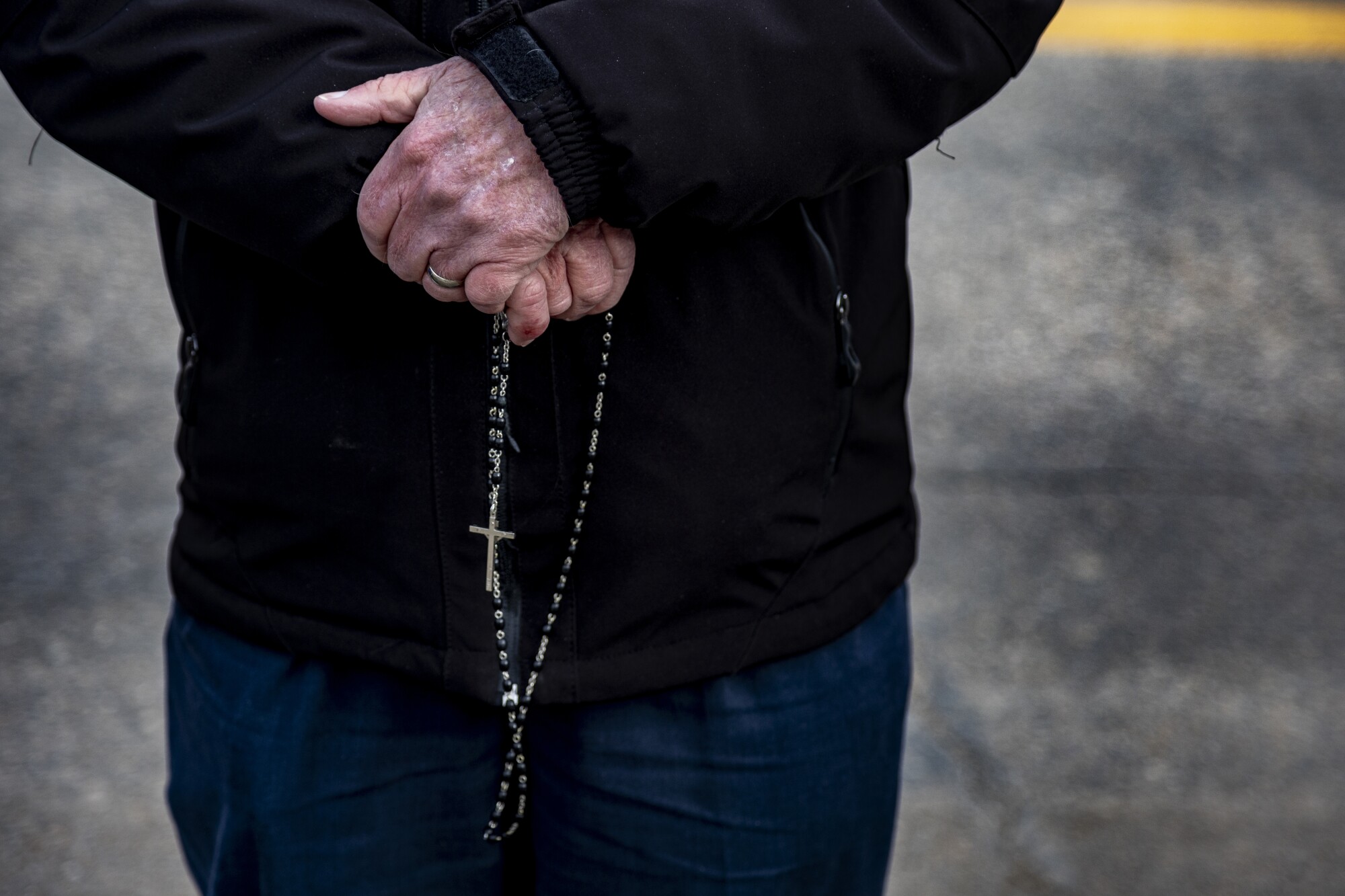 An antiabortion protester holds a rosary as he prays