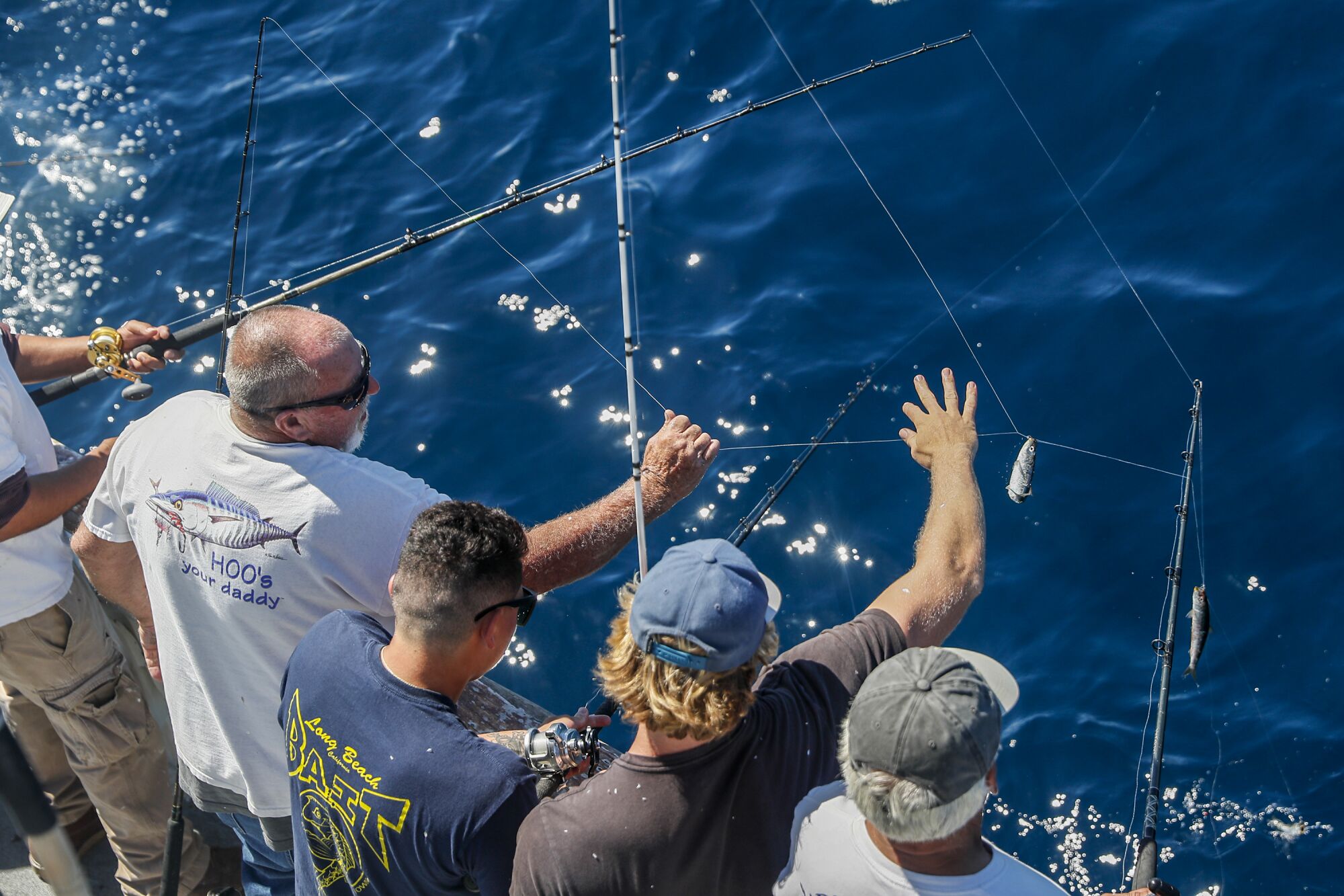 Fishermen stand shoulder to shoulder, becoming entangled with each other's lines.