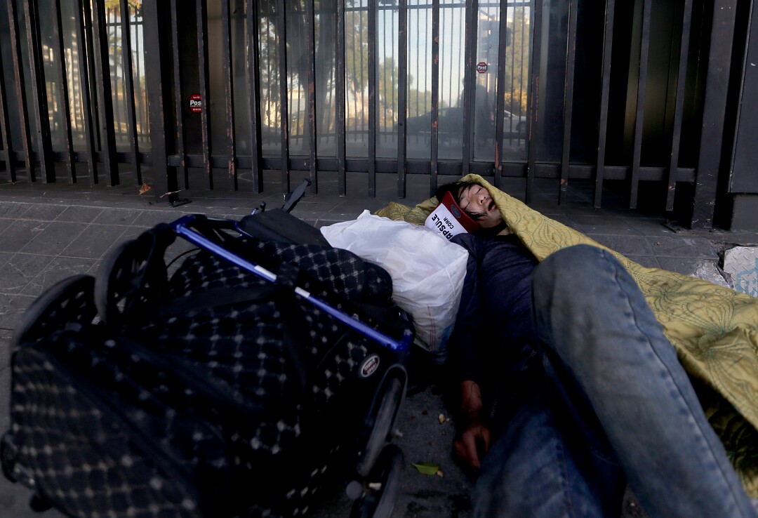A homeless man sleeps on the street in downtown Los Angeles