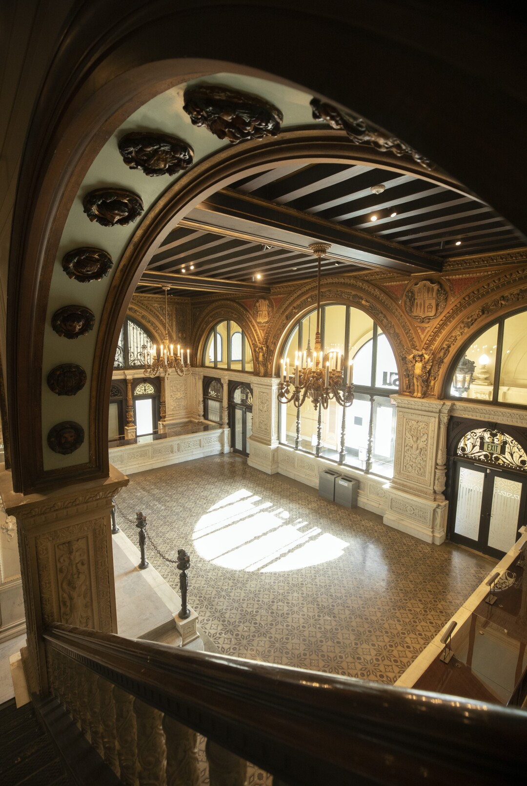 Sunlight streams through a window into the decorous lobby with Spanish tile floors and chandeliers.