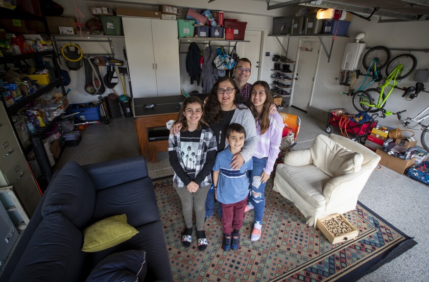 Bobby Sasson stands with her three children and her husband in their garage.