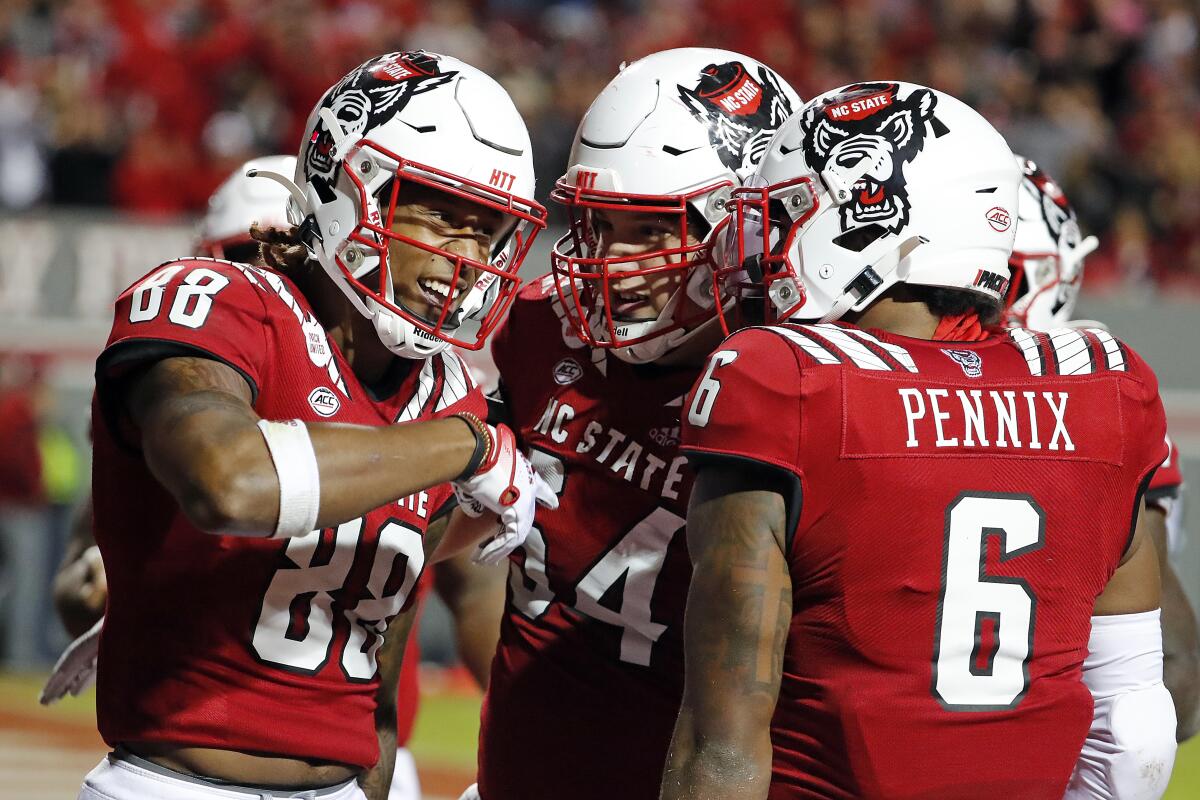 North Carolina State's Devin Carter (88) is congratulated on his touchdown by teammates Dylan McMahon (54) and Trent Pennix (6) during the second half of an NCAA college football game against Louisville in Raleigh, N.C., Saturday, Oct. 30, 2021. (AP Photo/Karl B DeBlaker)