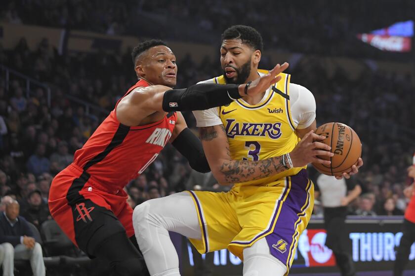 Houston Rockets guard Russell Westbrook, left, reaches for the ball held by Los Angeles Lakers forward Anthony Davis during the first half of an NBA basketball game Thursday, Feb. 6, 2020, in Los Angeles. (AP Photo/Mark J. Terrill)