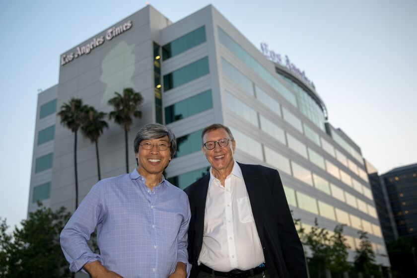 EL SEGUNDO, CA --JULY 28, 2018 --Patrick Soon-Shiong, MD, owner and executive chairman of the Los Angeles Times, left and Executive Editor Norman Pearlstine, are photographed with a silhouette of the late Jonathan Gold, former pulitzer-prize winning food critic for the Times, projected onto the side of the paper's headquarters in El Segundo, July 28, 2018. Gold was remembered across L.A., with buildings being bathed in gold lights as a tribute. (Jay L. Clendenin / Los Angeles Times)