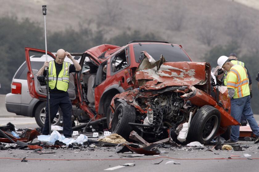 Steve Taggart, left, of the California Highway Patrol takes measurements at the wreckage of a car crash on the westbound 60 Freeway in Diamond Bar on Feb. 9 that left six people dead.