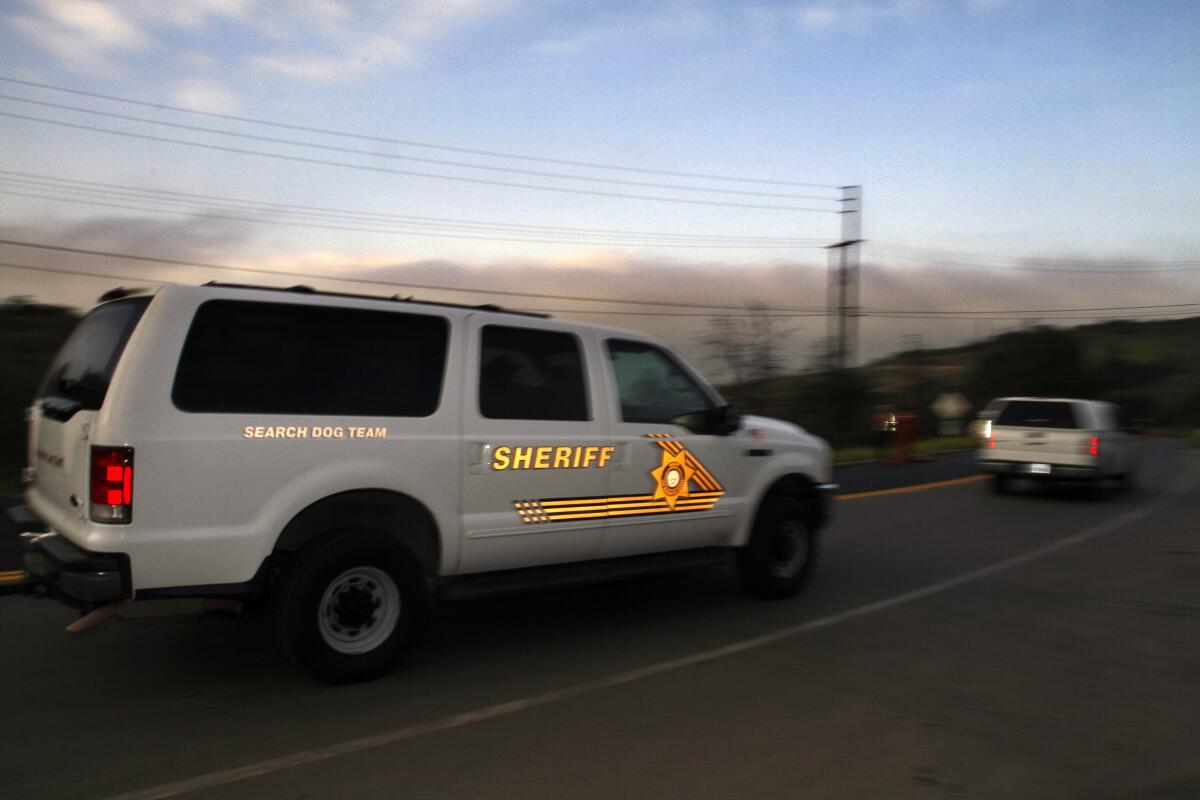 A white SUV with a logo that says "sheriff" is shown driving down a highway.