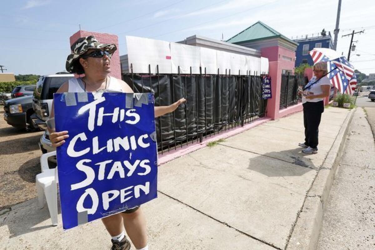 An abortion rights supporter, left, argues with an abortion opponent outside a clinic in Jackson, Miss.