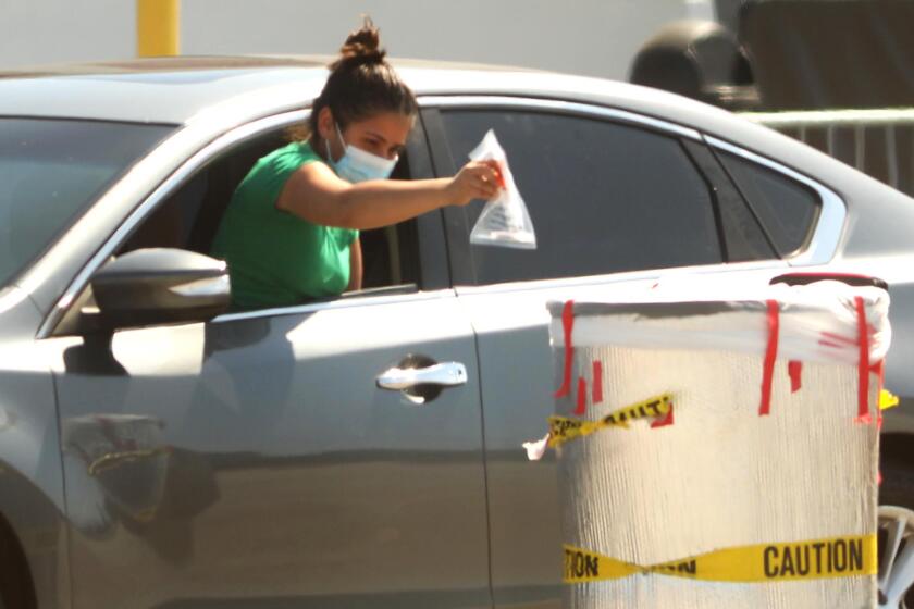 INGLEWOOD, CA - JULY 20, 2020 - - A woman deposits her coronavirus test in a bin at the COVID-19 testing site at The Forum parking lot in Inglewood on Monday, July 20, 2020. (Genaro Molina / Los Angeles Times)