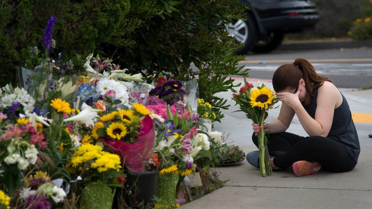 A woman sits next to flowers and messages of support at a makeshift memorial near the Chabad of Poway synagogue on Sunday.