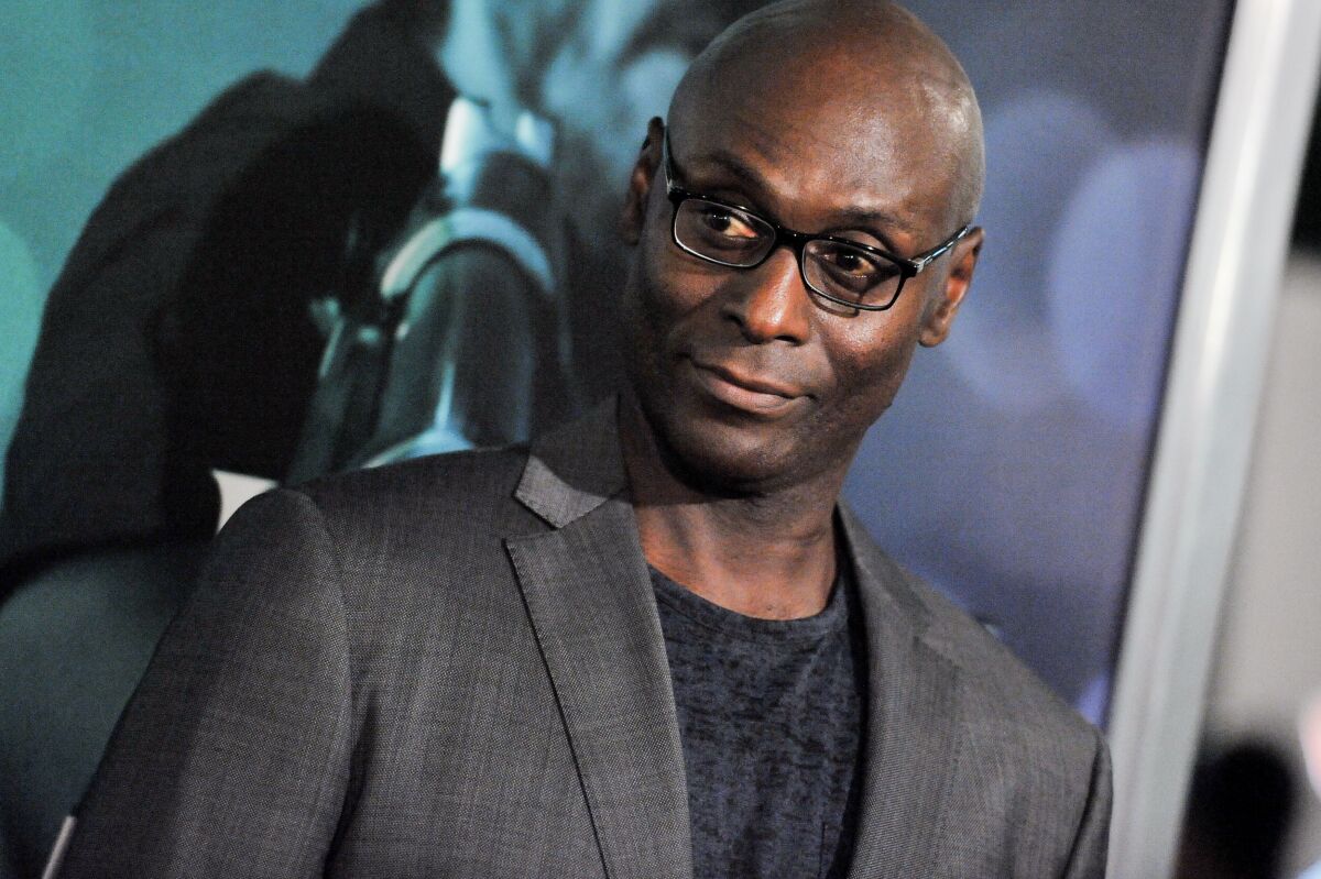 Lance Reddick in a suit looking to his right
