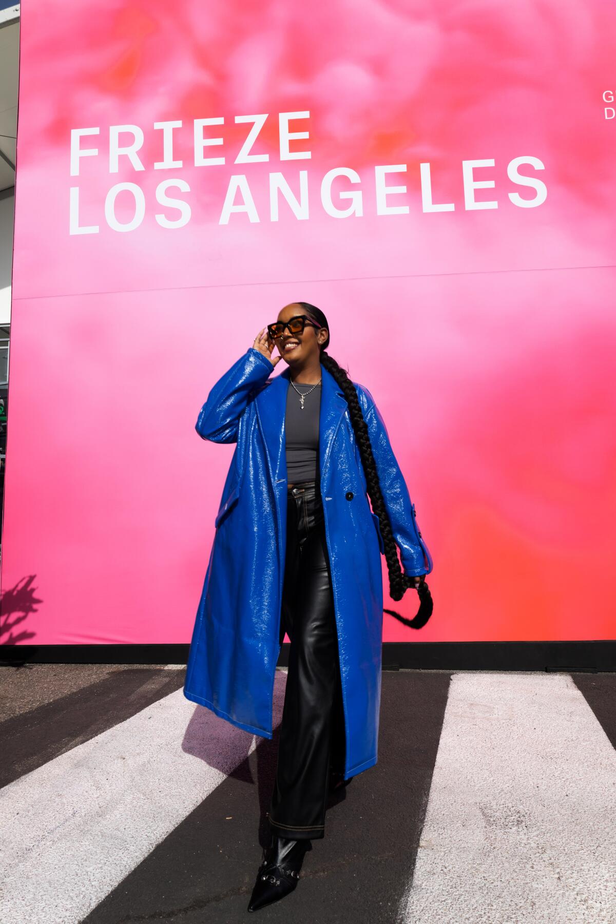 Delaney George stands in front of a wall that reads, "Frieze Los Angeles."