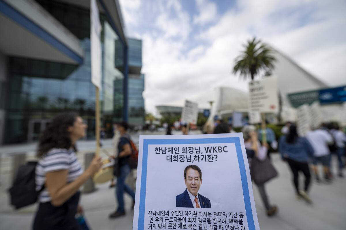 Protesters hand out a flier with a photo of Hannam Chain Chief Executive Kee Whan Ha at the Anaheim Convention Center.
