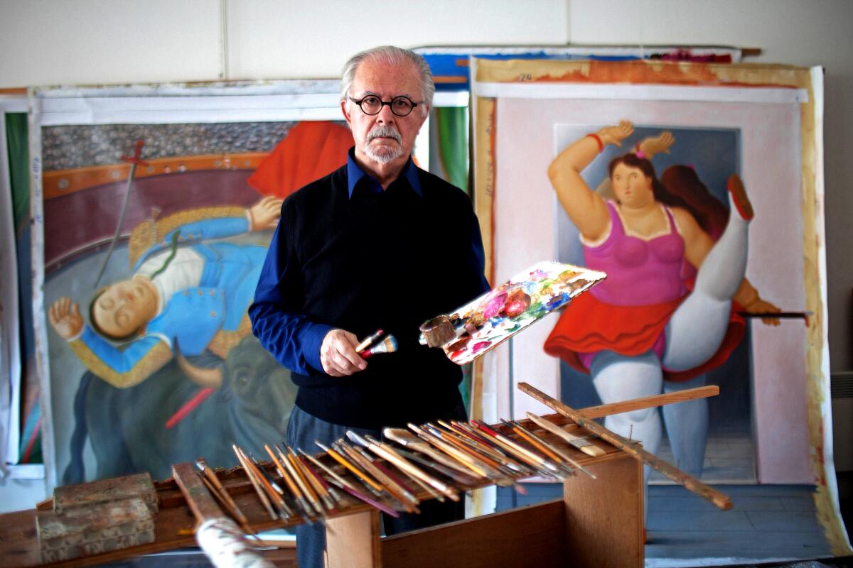 Fernando Botero holds paints and brushes in his studio.