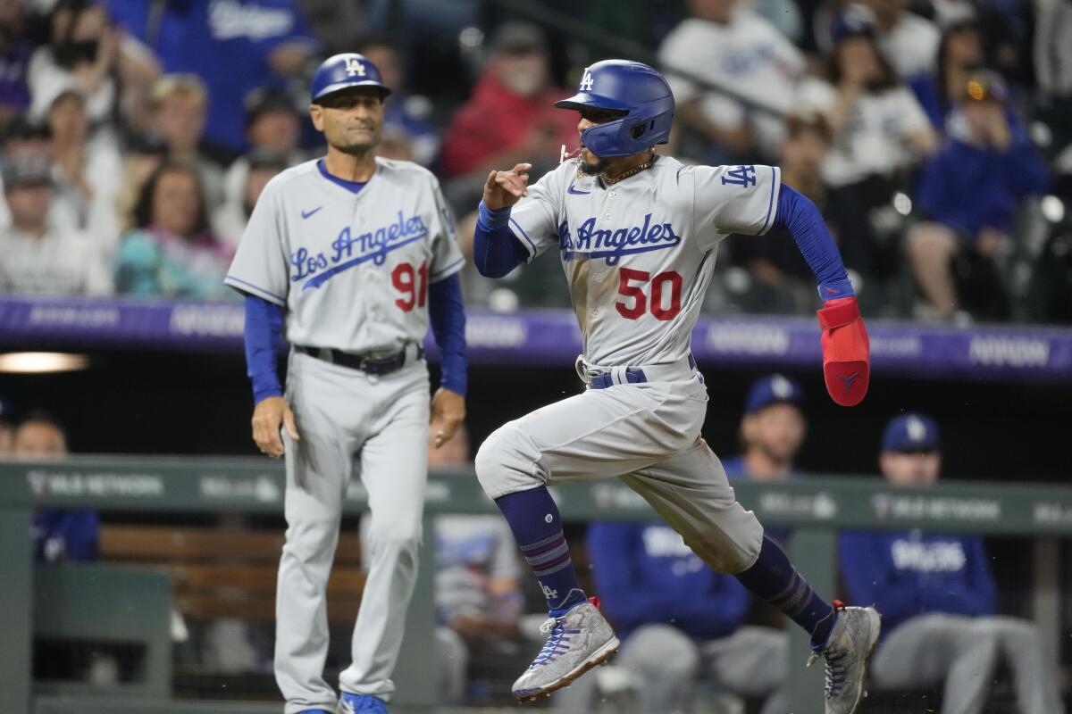 Mookie Betts, de los Dodgers de Los Ángeles, pasa corriendo por delante del entrenador