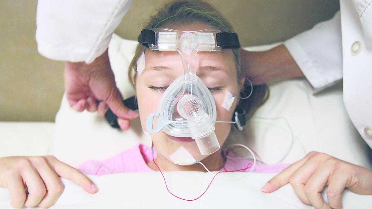 A patient at the Sleep Disorders Center is connected to a CPAP device by Lead Technologist Janice Roby, a device that delivers oxygen and opens passageways that allows for better breathing for research.