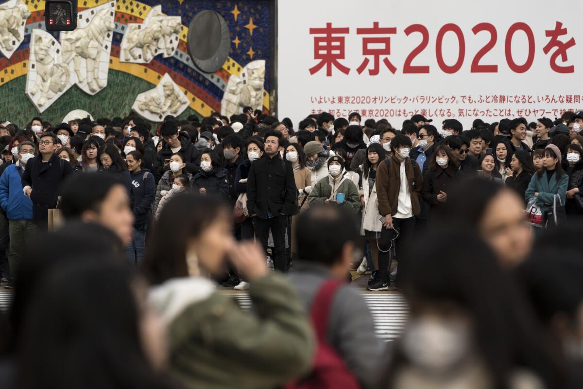 People wearing masks wait to cross a street Feb. 2 in Tokyo.