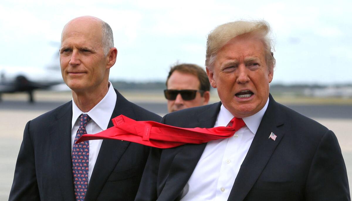 Accompanied by Florida Gov. Rick Scott, left, President Trump arrives at Orlando International Airport on Monday. The president was in Orlando to deliver remarks to the International Assn. of Chiefs of Police.