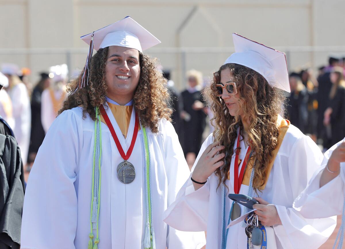 Colorful graduates Jake Alvarez, a double Tower Award winner, and Samantha Shaw, from left, participate in Tuesday's ceremony