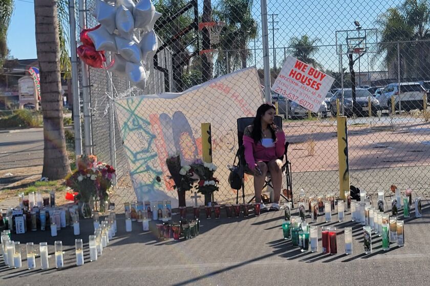 Friends leave flowers and candles on Monday at a parking lot in Compton near N Bullis Road, a day after two Latino men were shot and killed in a car that was parked near an illegal street takeover.