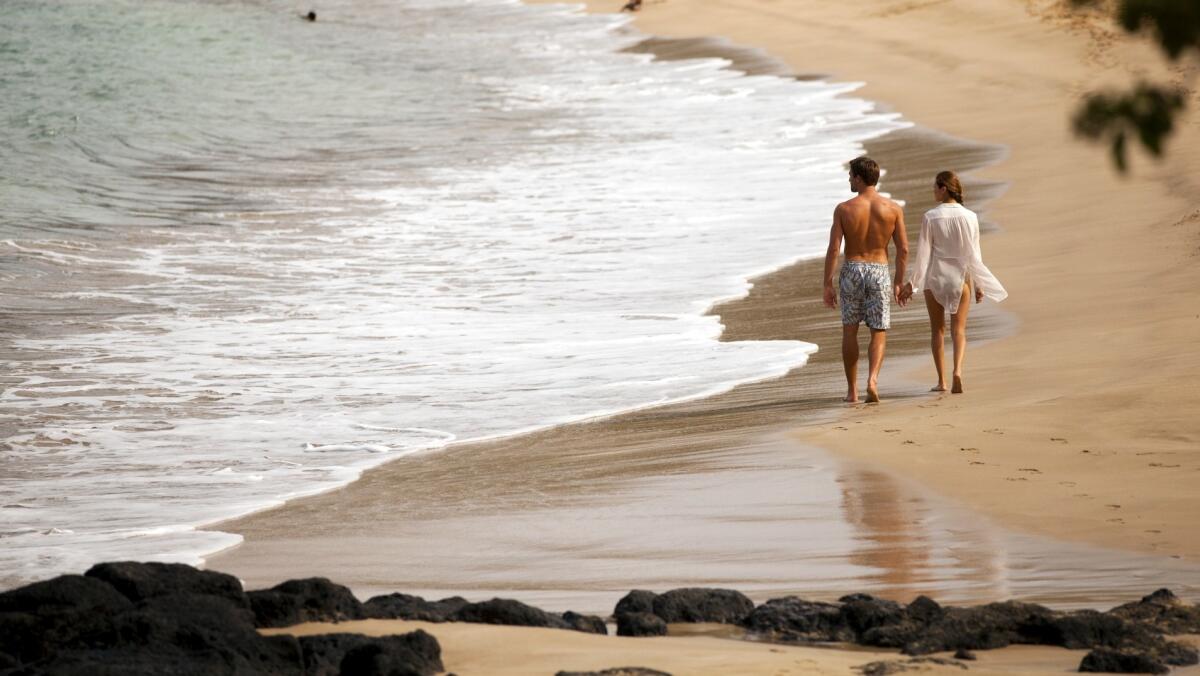 Visitors to Lanai stroll along a deserted beach at Manele Bay.