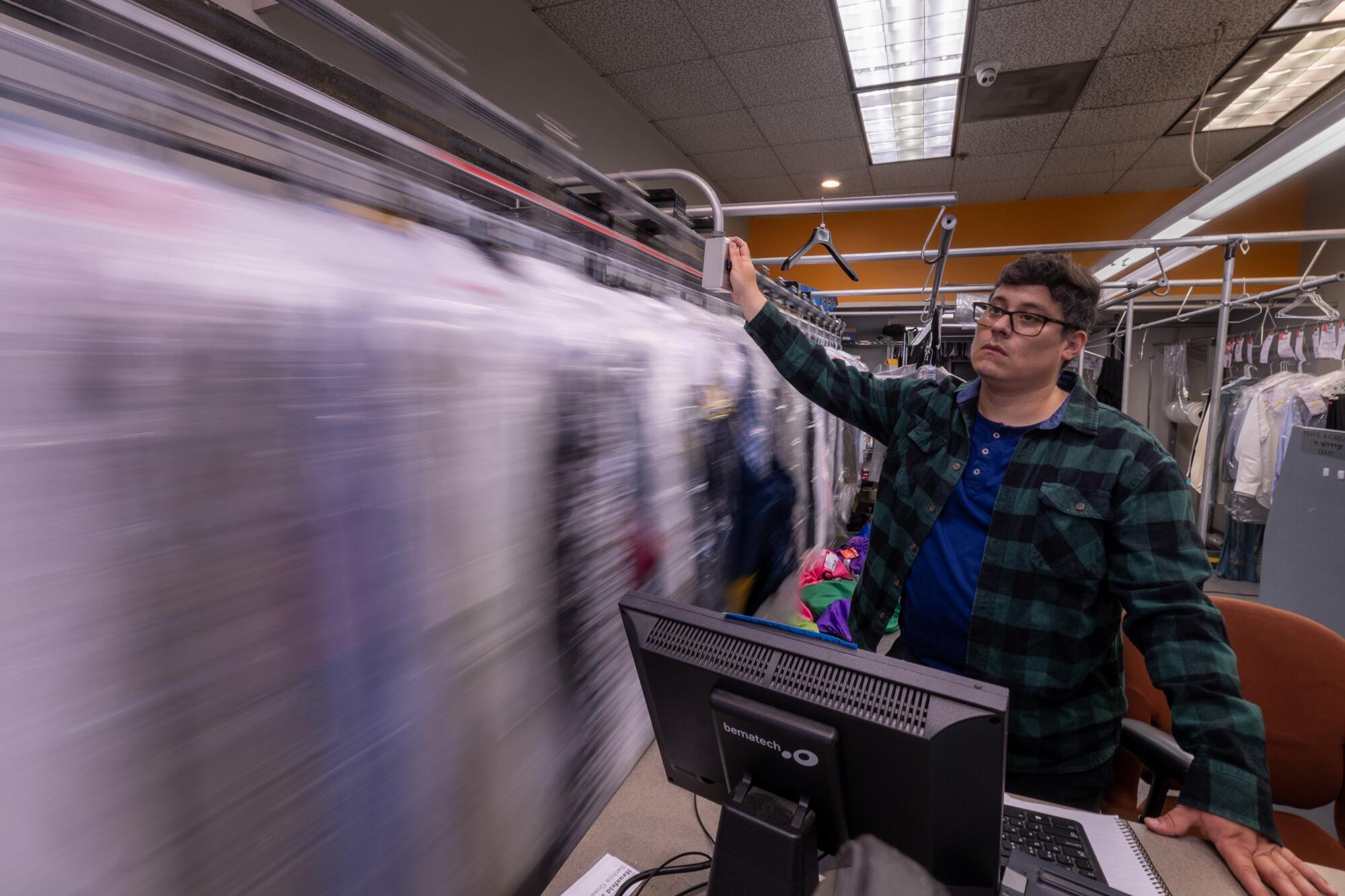 Cleaners Depot employee Santiago Lopez rotates a conveyor belt of garments.