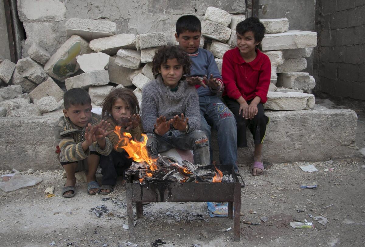 Syrian children warm themselves by a fire in the eastern rebel-held Tal Zarzour neighborhood in Aleppo, northern Syria, on Sunday.