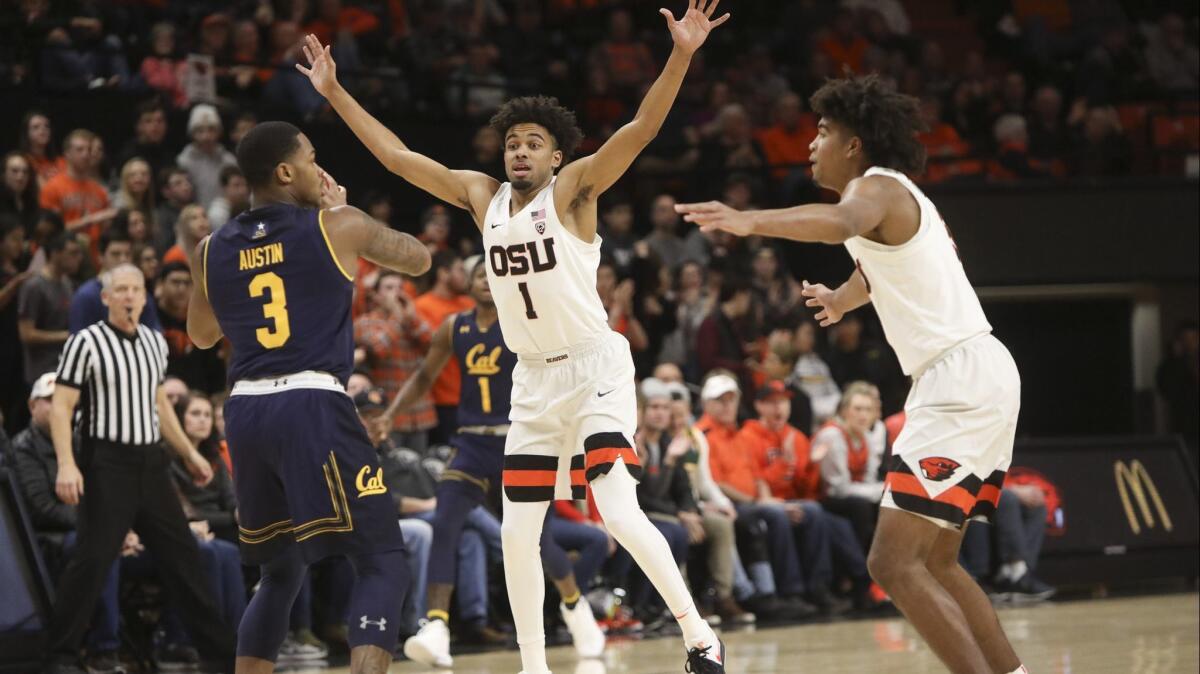California's Paris Austin (3) looks to pass as Oregon State's Stephen Thompson Jr. (1) and Ethan Thompson (5), right, defend during the first half on Saturday.