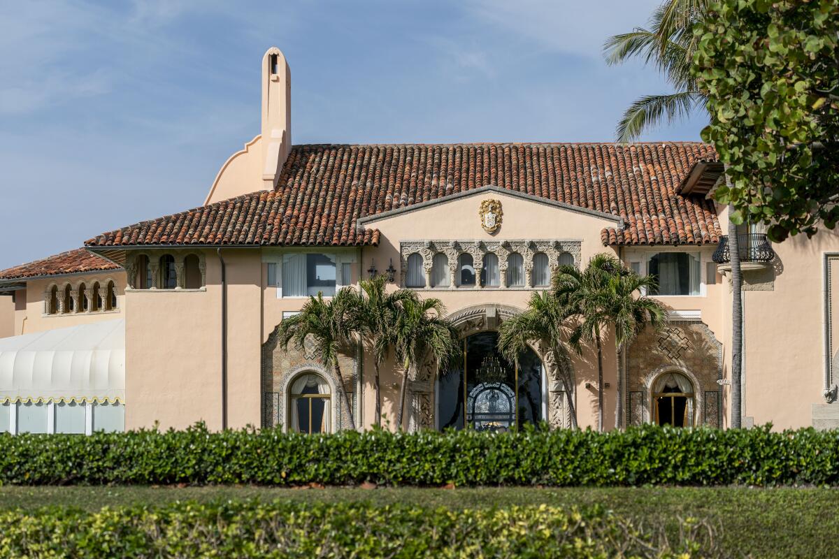  Pink stucco facade with palms around an arched doorway 