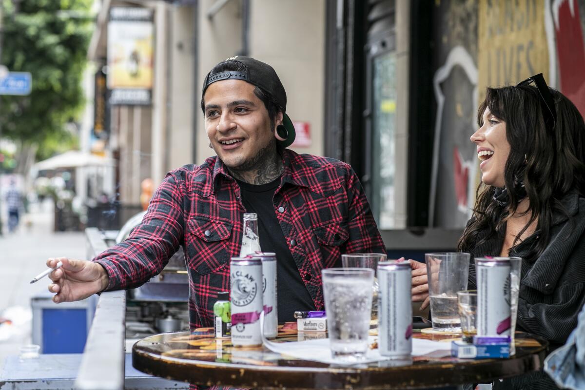 Two people sit at an outdoor table with drinks at the Down & Out sports bar in downtown Los Angeles