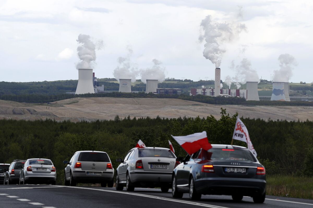 FILE - Cars drive slowly to block a border between Czech Republic and Poland near the Turow coal mine near Bogatynia, Poland, Tuesday, May 25, 2021. Poland is recalling its new ambassador to Prague after he criticized the country’s approach to a dispute with the Czech Republic over a state-run coal mine. The open-pit lignite mine is located near the border between the two countries, and Czech authorities have said it negatively affects the environment and drains water from local villages. (AP Photo/Petr David Josek, File)