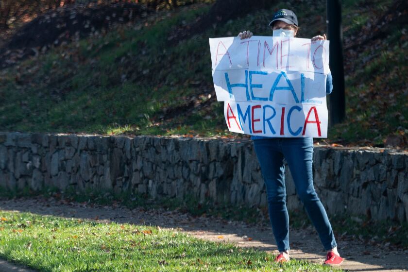 A woman holds up a sign as the motorcade of US President Donald Trump passes on the way to the Trump International Gold club in Sterling, Virginia on November 8, 2020. - World leaders rushed to congratulate US president-elect Joe Biden, with many expressing hopes of unity and cooperation following four years of explosive Donald Trump diplomacy. (Photo by ANDREW CABALLERO-REYNOLDS / AFP) (Photo by ANDREW CABALLERO-REYNOLDS/AFP via Getty Images)