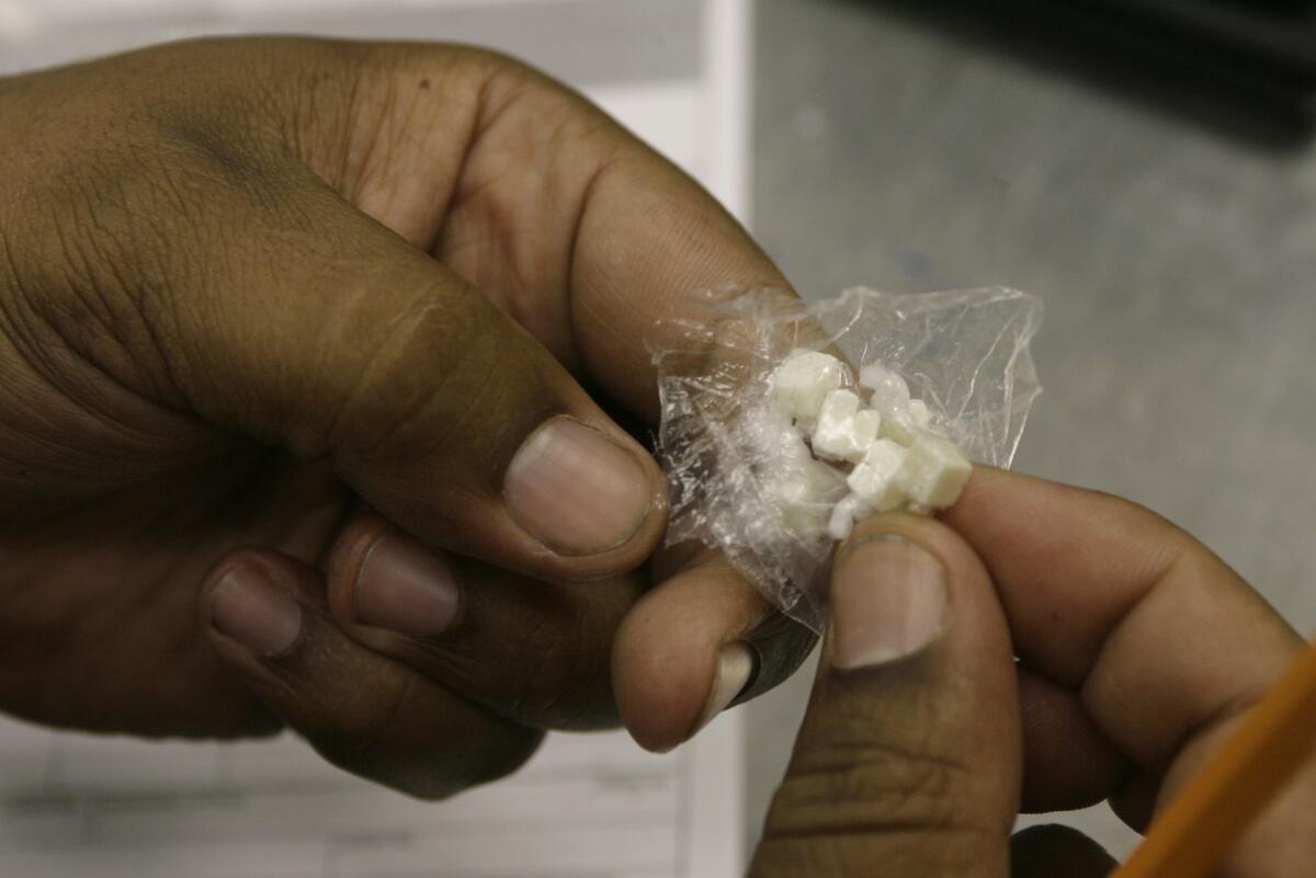 A Los Angeles police officer counts the number of doses of crack cocaine, as he files an evidence police report after a drug related arrest in the skid row area of downtown Los Angeles.