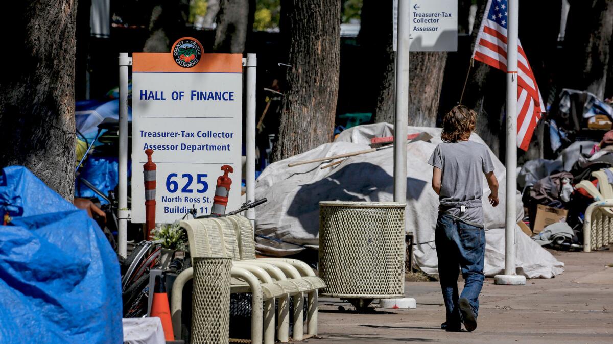 A homeless person walks past one of the encampments next to the Hall Of Finance in the Civic Center Plaza.