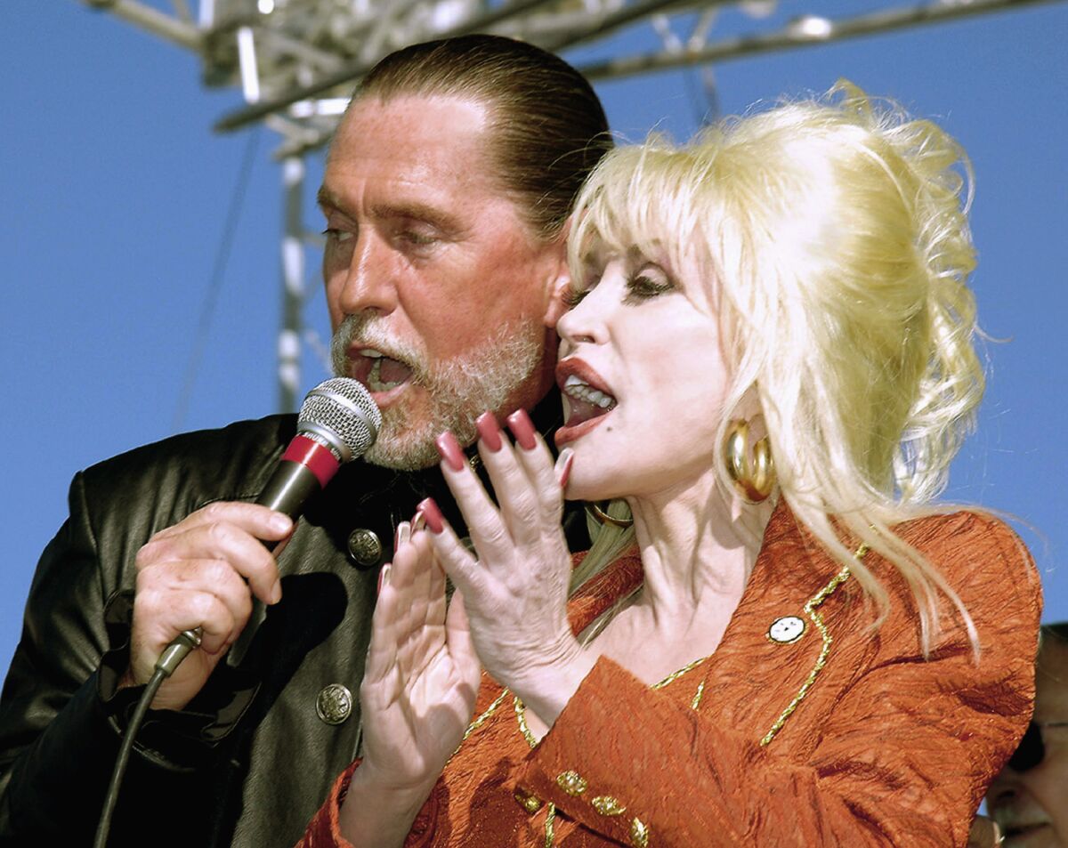 Randy and Dolly Parton share a microphone at the Carolina Crossroads groundbreaking.