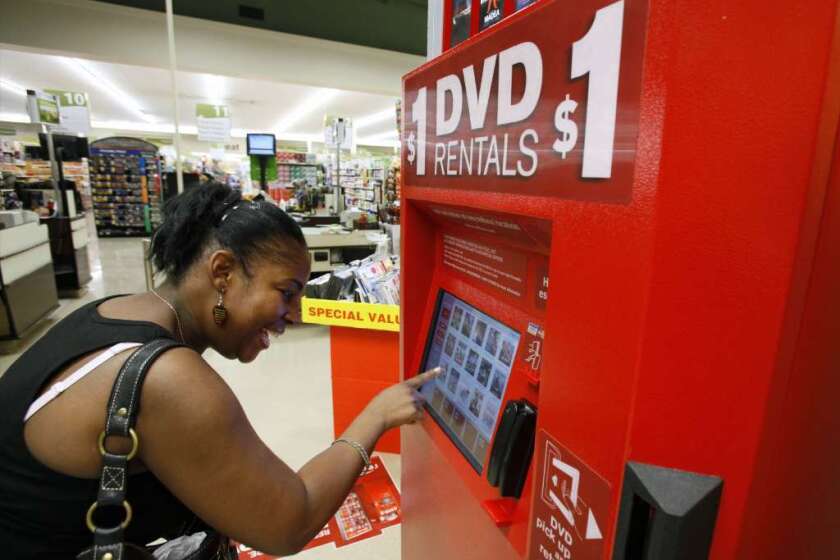 A woman selects a DVD at a Redbox kiosk in 2009. The company will be sold to Apollo Global Management for $1.6 billion.