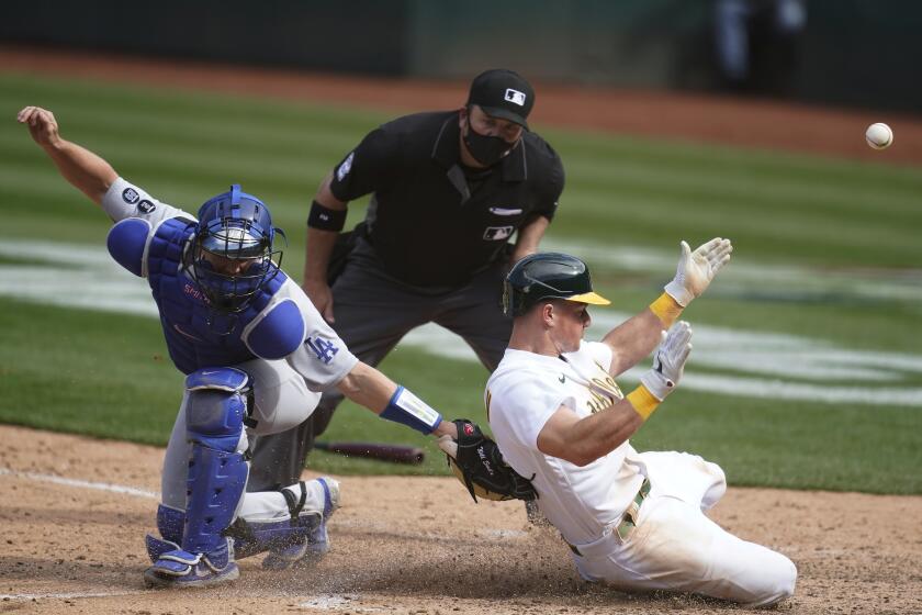 Oakland Athletics' Matt Chapman, right, slides home to score past Los Angeles Dodgers catcher Will Smith during the ninth inning of a baseball game in Oakland, Calif., Wednesday, April 7, 2021. (AP Photo/Jeff Chiu)