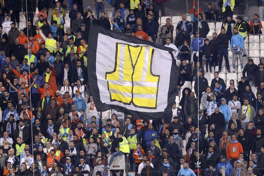 A supporter of Marseille waves a flag representing a giant yellow jacket, in solidarity with the movement of the demonstrators, called yellow jackets, who protest against the rising of the fuel taxes, during the League One soccer match between Marseille and Reims at the Velodrome stadium, in Marseille, southern France, Sunday, Dec. 2, 2018. (AP Photo/Claude Paris)