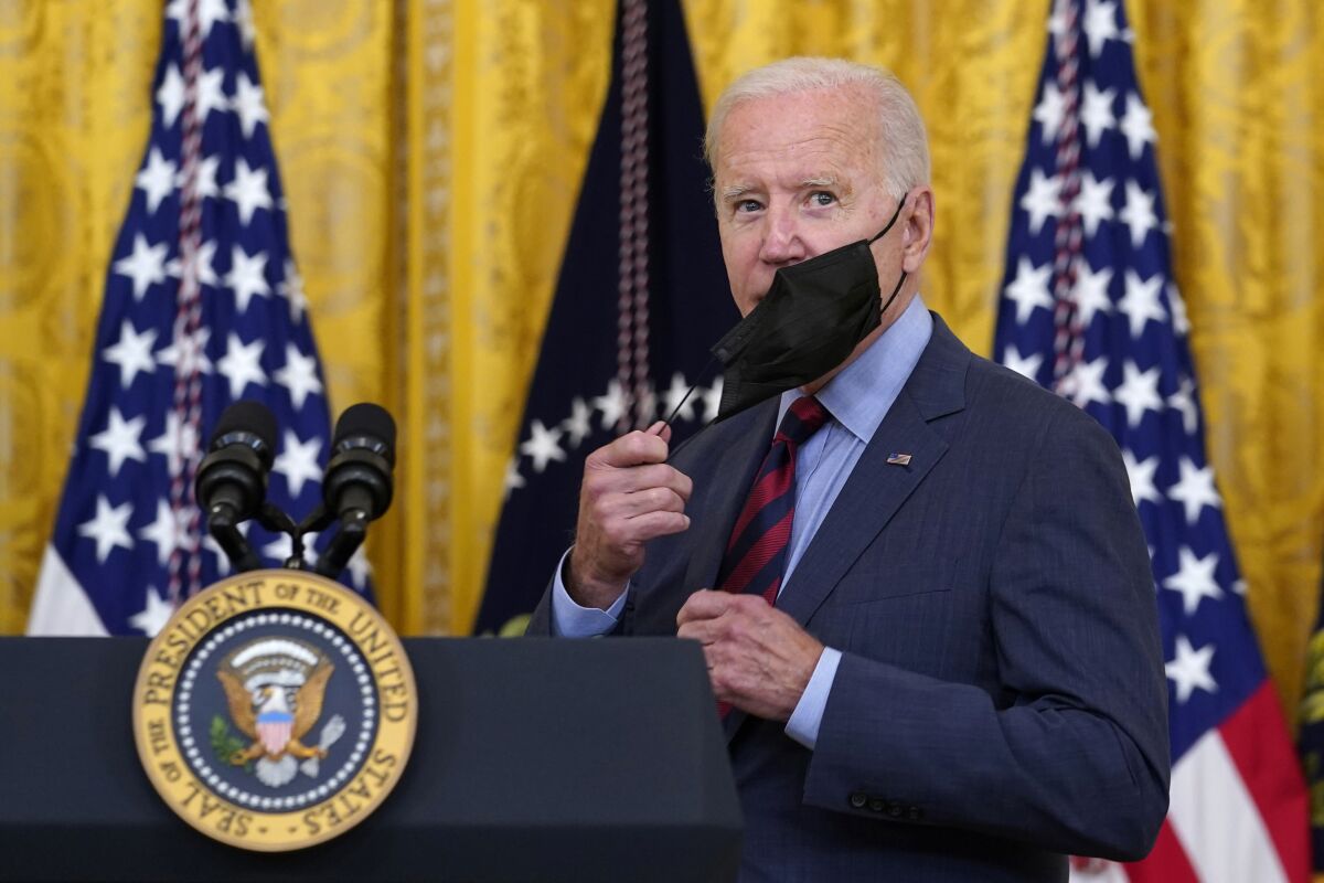 President Joe Biden takes off his mask as he arrives to speak about the coronavirus pandemic in the East Room of the White House in Washington, Tuesday, Aug. 3, 2021. The U.S. has donated and shipped more than 110 million doses of COVID-19 vaccines to more than 60 countries, ranging from Afghanistan to Zambia, the White House announced Tuesday. (AP Photo/Susan Walsh)