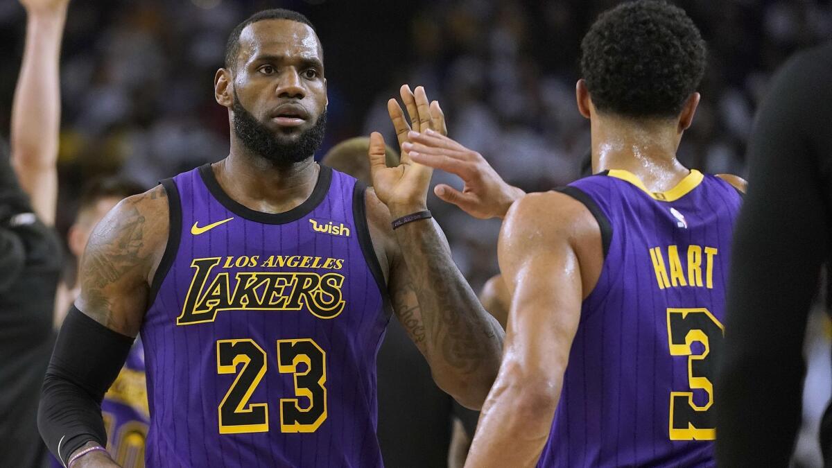 Lakers forward LeBron James high-fives Josh Hart at the end of the first half against the Golden State Warriors on Tuesday in Oakland.
