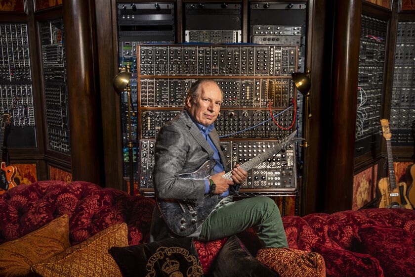 Santa Monica, CA - February 10: Oscar-winning film composer Hans Zimmer is photographed in support of his 2022 Oscar nomination for the film, “Dune,” at his Remote Control Productions, Inc. office in Santa Monica, CA, Thursday, Feb.10, 2022. Zimmer is photographed in front of a synthesizer made from various models by industry leaders, including Moog, PPG and MacBeth. The guitar Zimmer is holding and strumming is a Veleno, which he originally bought when he was 18, had to pawn in the 80’s to pay bills and eventually was able to track down years later and re-purchase it, saying, “It cost me a fortune to get it back!” (Jay L. Clendenin / Los Angeles Times)