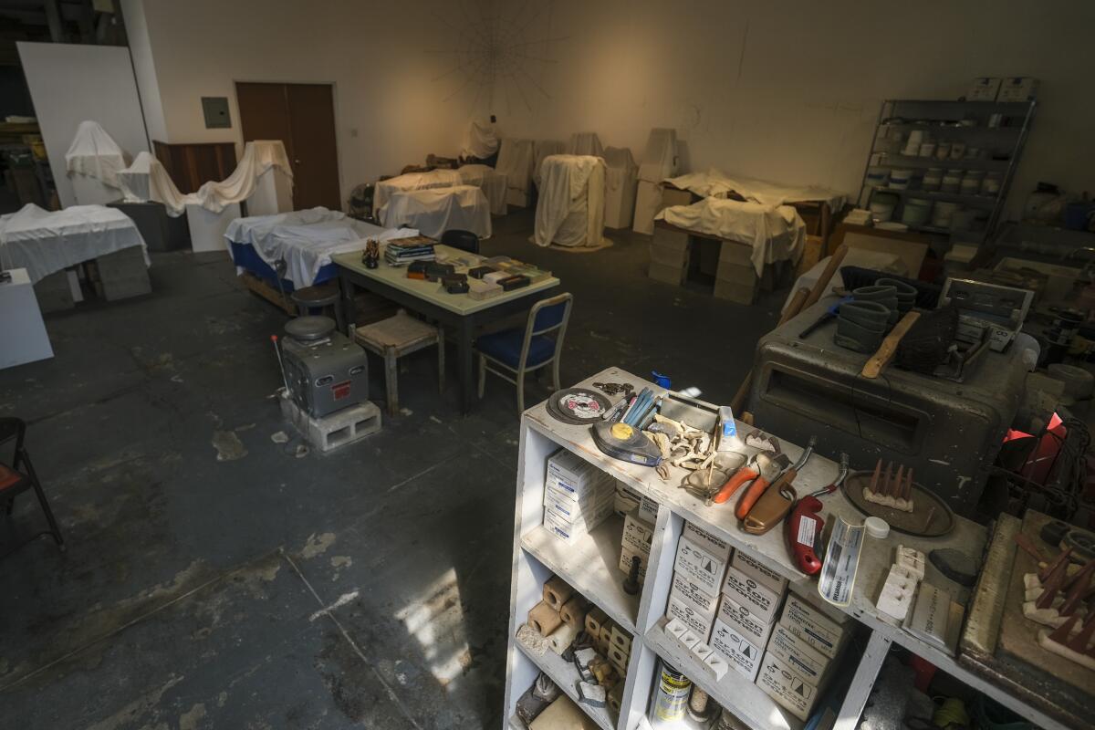 Shelves and tables hold tools and artworks in an artist's studio