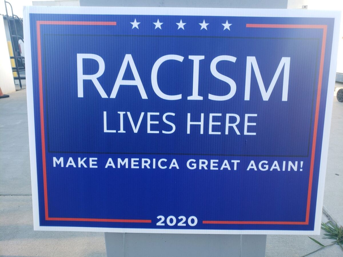 A lawn sign reads: "Racism lives here. Make America great again!" 