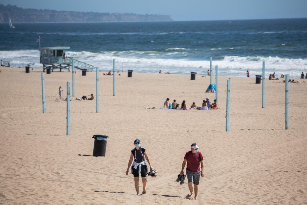 People walk along the sand in Manhattan Beach on Friday.