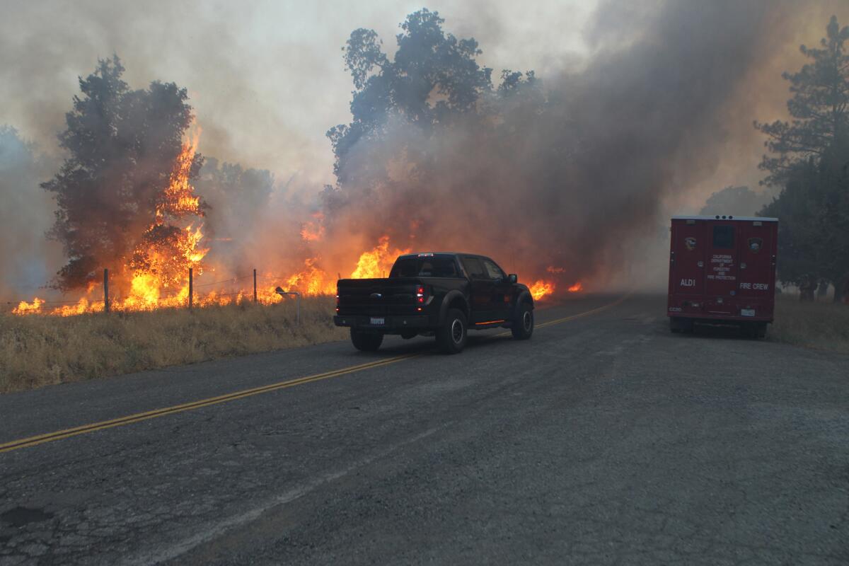 A truck makes its way Friday past the Bully fire near Ono, Calif. A man is facing an involuntary man slaughter charge in connection with the fire.