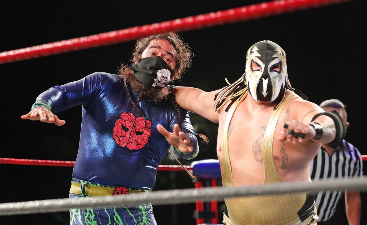 Flecha Fugaz, right, drives Chaz Herrera into the ropes during Fight Club OC's drive-in pro wrestling show.