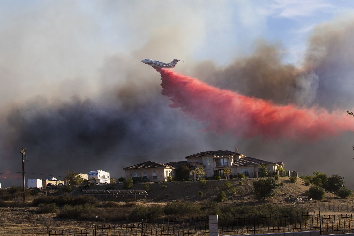 A plane drops fire retardant near a home to stop the wind driven Liberty Fire near Los Alamos Road.